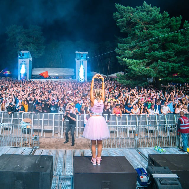 CANDICE making a heart above her head as she faces a packed forest festival crowd