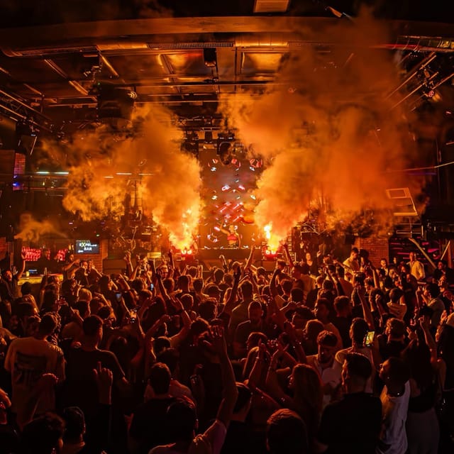 CANDICE performing to a packed club crowd as orange smoke jets erupt around the DJ booth