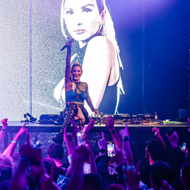 CANDICE sitting on the edge of the Duplex Prague DJ booth beneath a large portrait on the LED screen