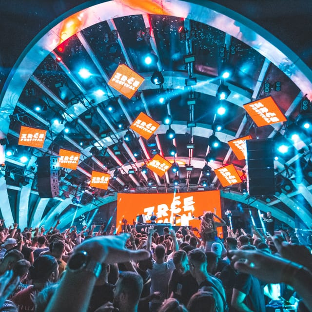Wide view of a packed Zrće Festival crowd facing the circular main stage under blue lights
